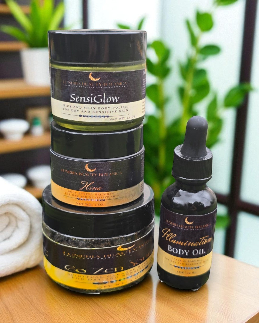 Stack of skincare products with a bottle of body oil on a wooden surface.